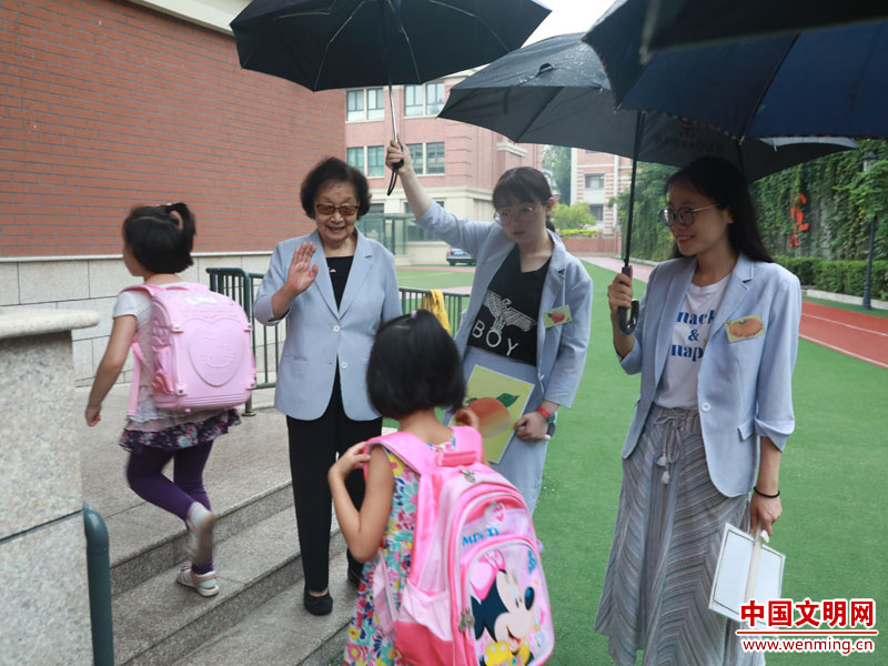 每逢下雨天，老师们都会撑伞排成一队护送学生进教学楼。而王希萍（左二）一定会候