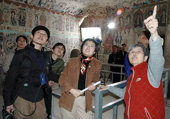 2004年10月，樊锦诗在莫高窟第285窟向《敦煌再发现》剧组人员讲解洞窟内容