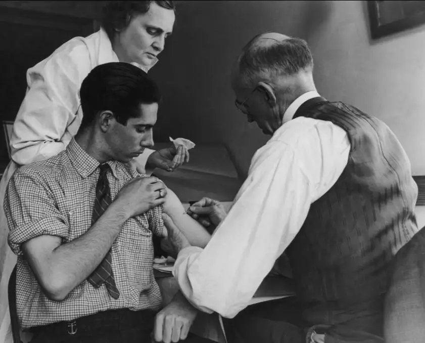 1938年3月，纽约的加斯波特，校医和护士为一名年轻人接种天花疫苗。