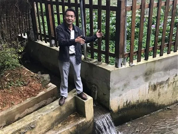 红河州生态环境局元阳分局局长罗成会向记者介绍大鱼塘村村民生活污水集中处理情况