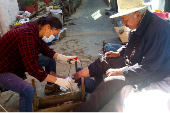 次仁卓玛（左）帮阿旺群培老人洗脚、换药。资料图