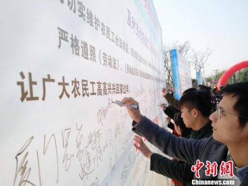 资料图：企业代表在背景墙签署《及时支付农民工工资承诺书》。　王剑 摄